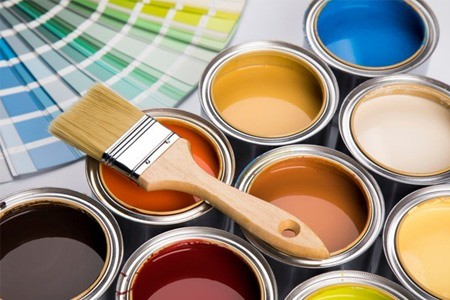 A paintbrush atop several paint cans