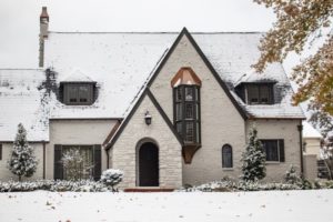 a painter brick home with snow on the roof and lawn