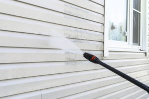 a person pressure washing the outside of their house