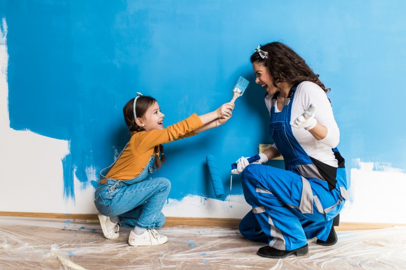 mother and daughter laughing while painting room